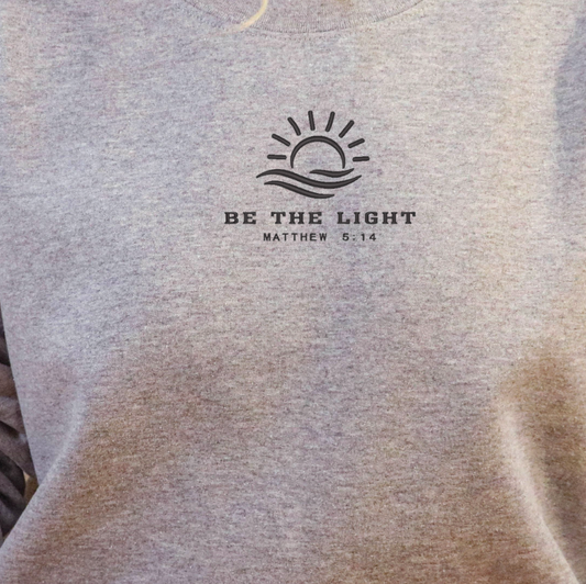 Close-up of Be the Light Matthew 5:14 embroidery on a gray crewneck sweatshirt